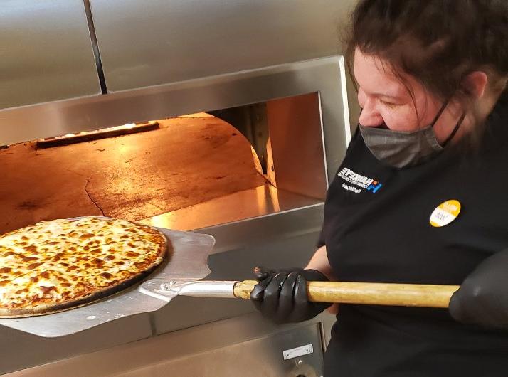 A student at the RedTail Cafe prepares pizza